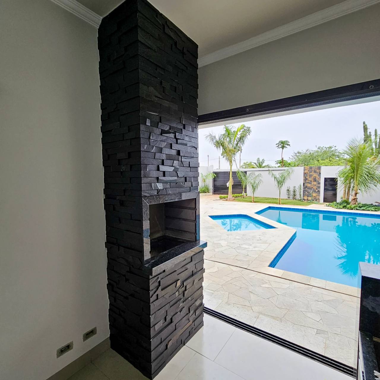 Churrasqueira da chácara revestida com filete de Pedra Ferro Preta, junto à piscina